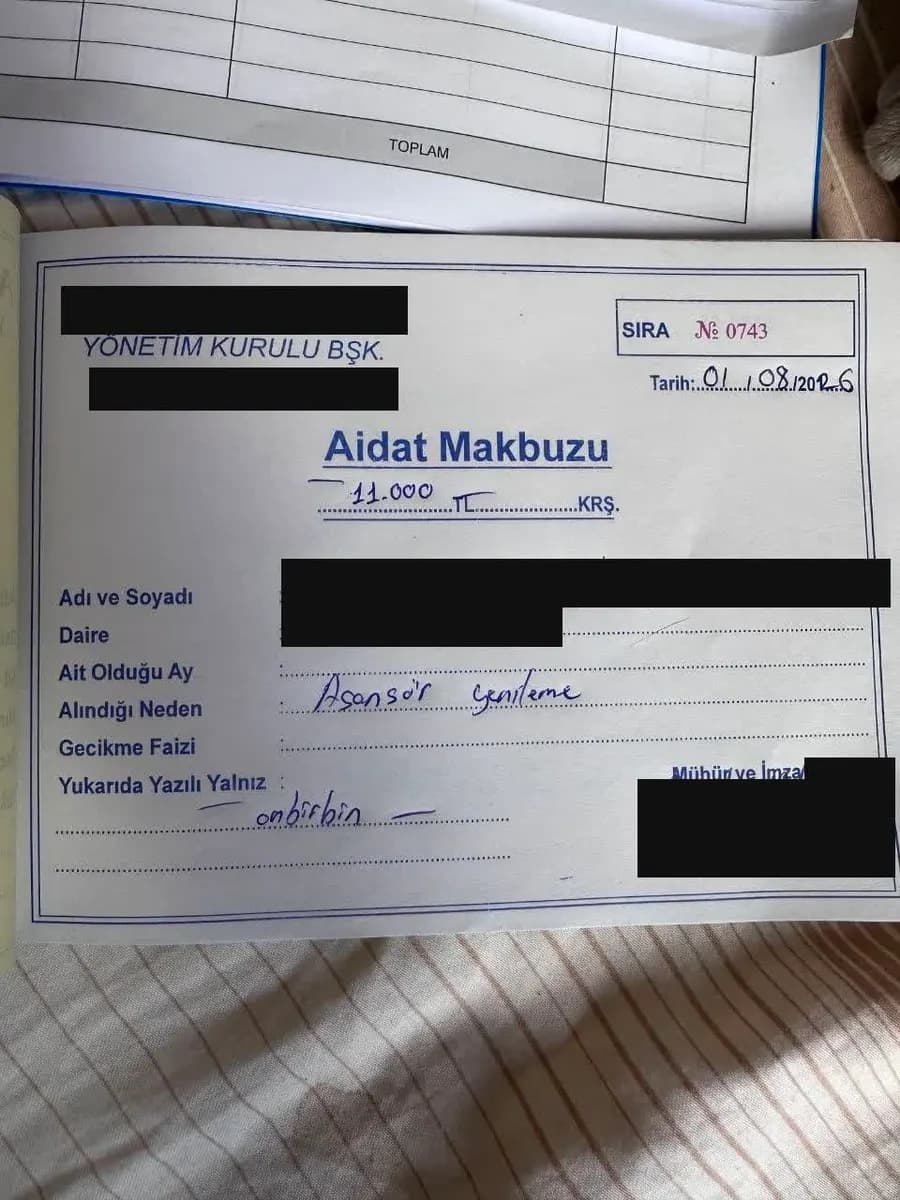 Квитанция Aidat Makbuzu на 11.000 TL, заполненная от руки, имя, квартира и подпись закрыты чёрными плашками